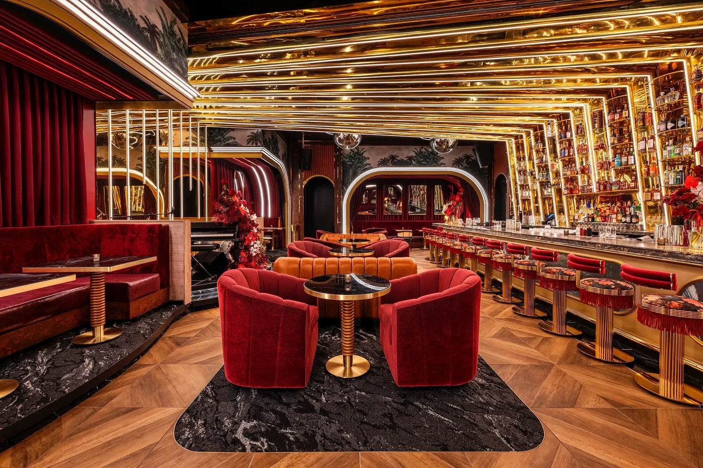 Luxurious venue lounge with red velvet seating, ornate gold archway, and professional entertainment lighting
