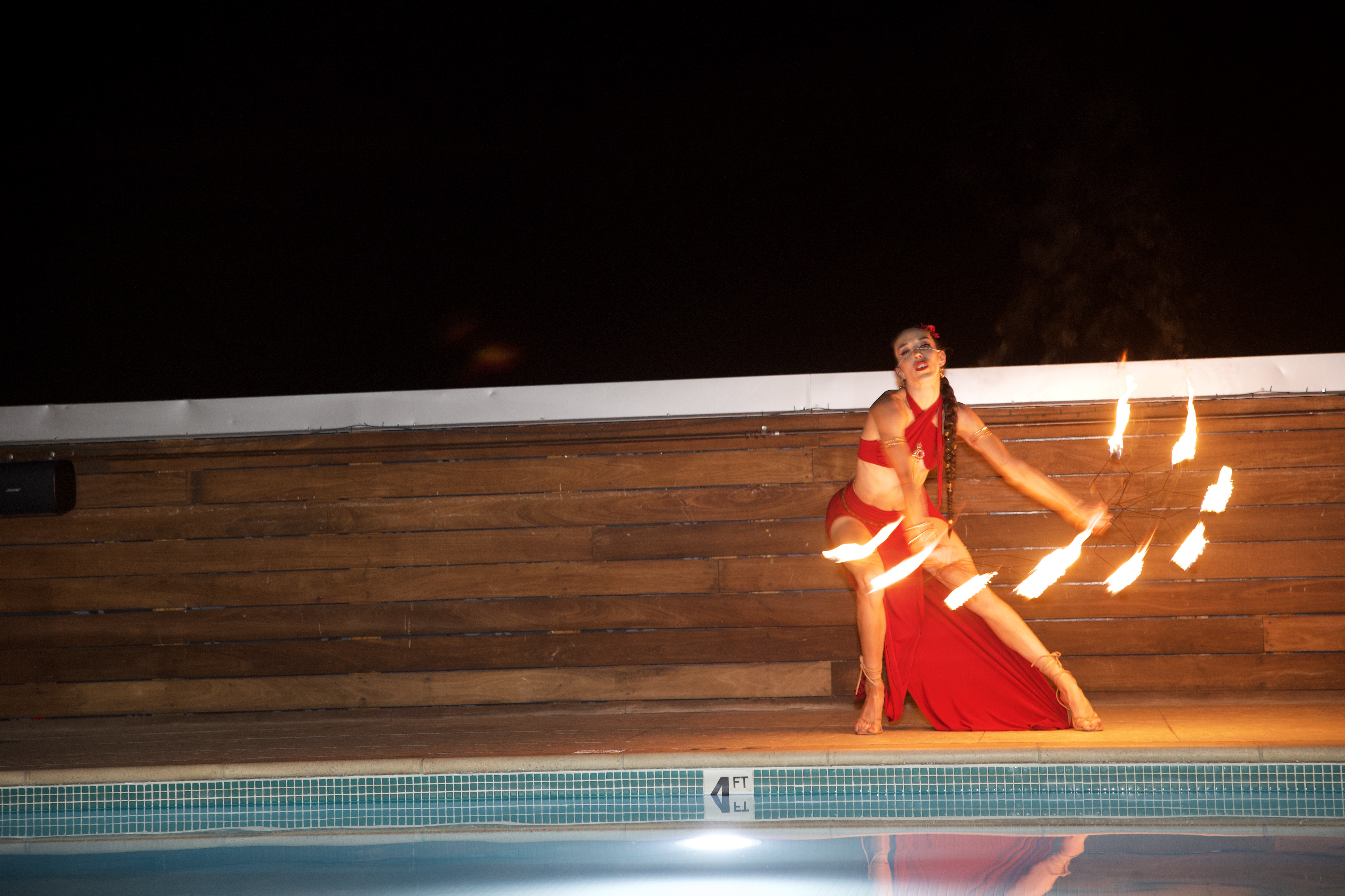 Fire performer with flaming fans poolside at a luxury event