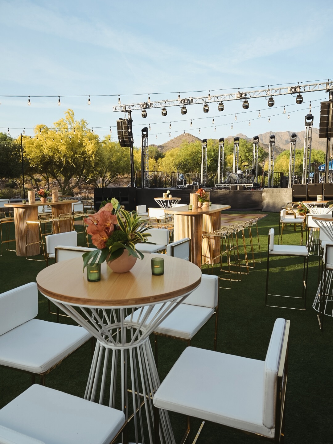 Outdoor event setup with stage lighting and desert mountains at an Arizona country club