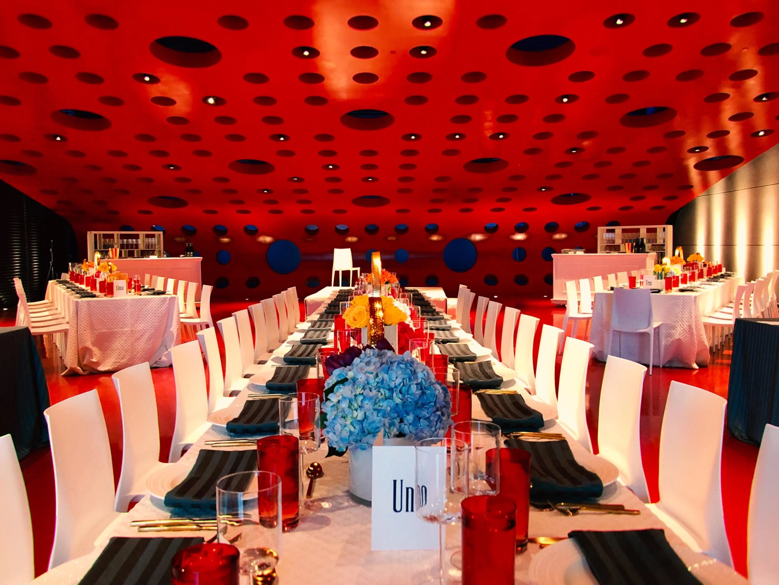 Elegant corporate dinner setup with striking red ceiling and formal table settings